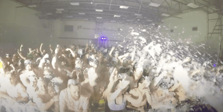 A vibrant indoor glow party with energetic crowd and colorful lighting.