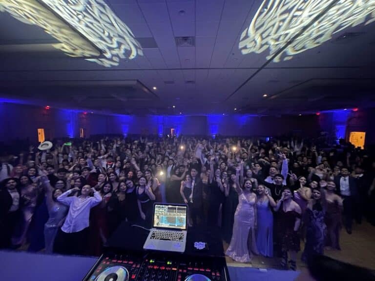 Large crowd dancing at Operation Glow event with vibrant lighting and DJ setup.