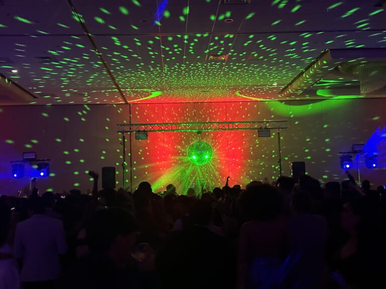 Laser light show at OPERATION GLOW event with vibrant green and red lights illuminating the crowd.