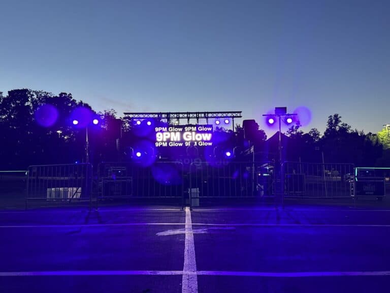 Vibrant outdoor glow event stage with purple lighting and digital signage for OPERATION GLOW.